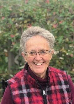 Darlene Fitkin smiling outdoors in a red plaid vest.