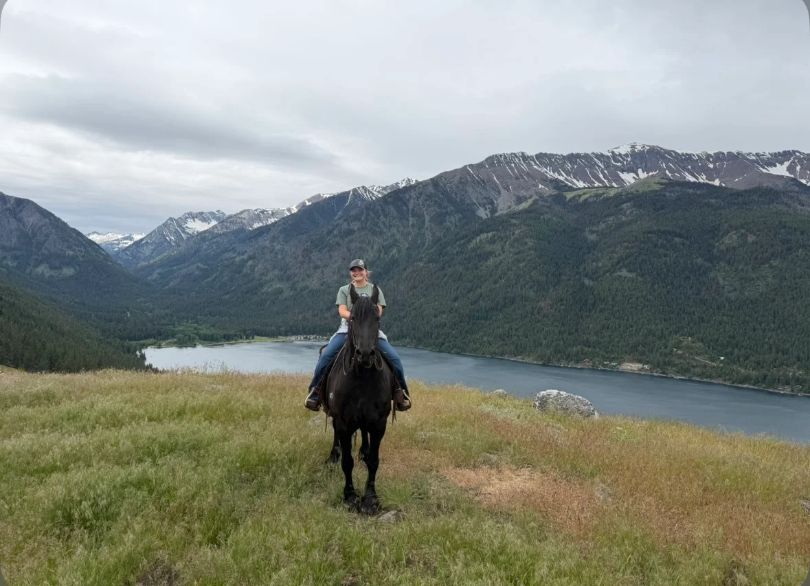 Grace Collins on a black horse overlooking a mountain lake.